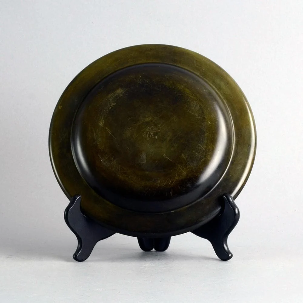 a black and gold plate sitting on a stand