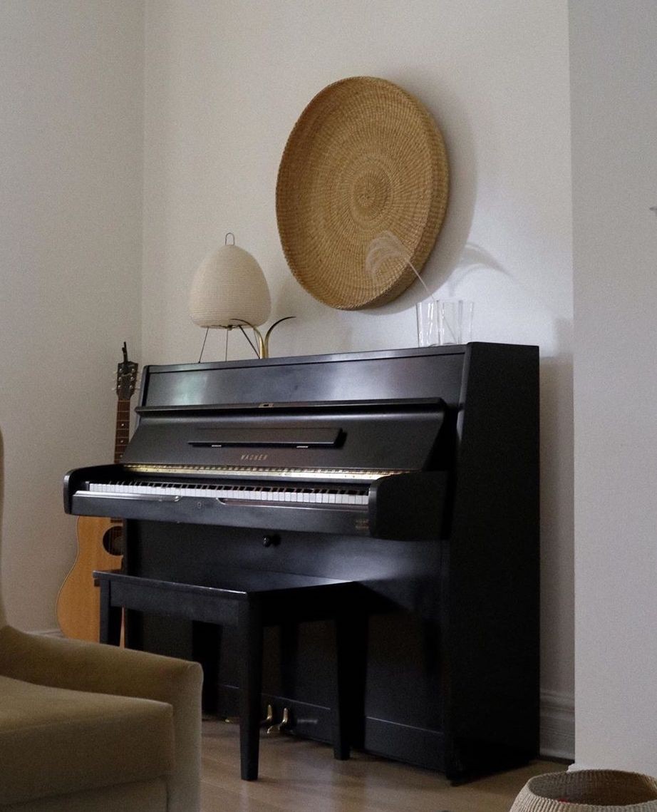 a black piano sitting in a living room next to a lamp