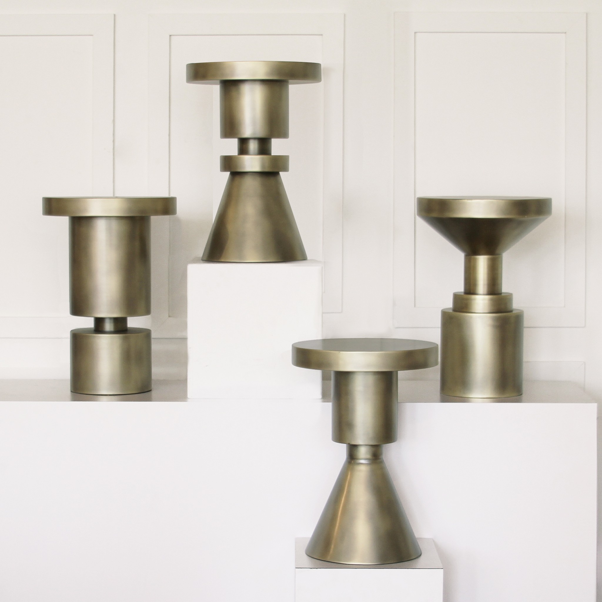 a group of three metal vases sitting on top of a white shelf