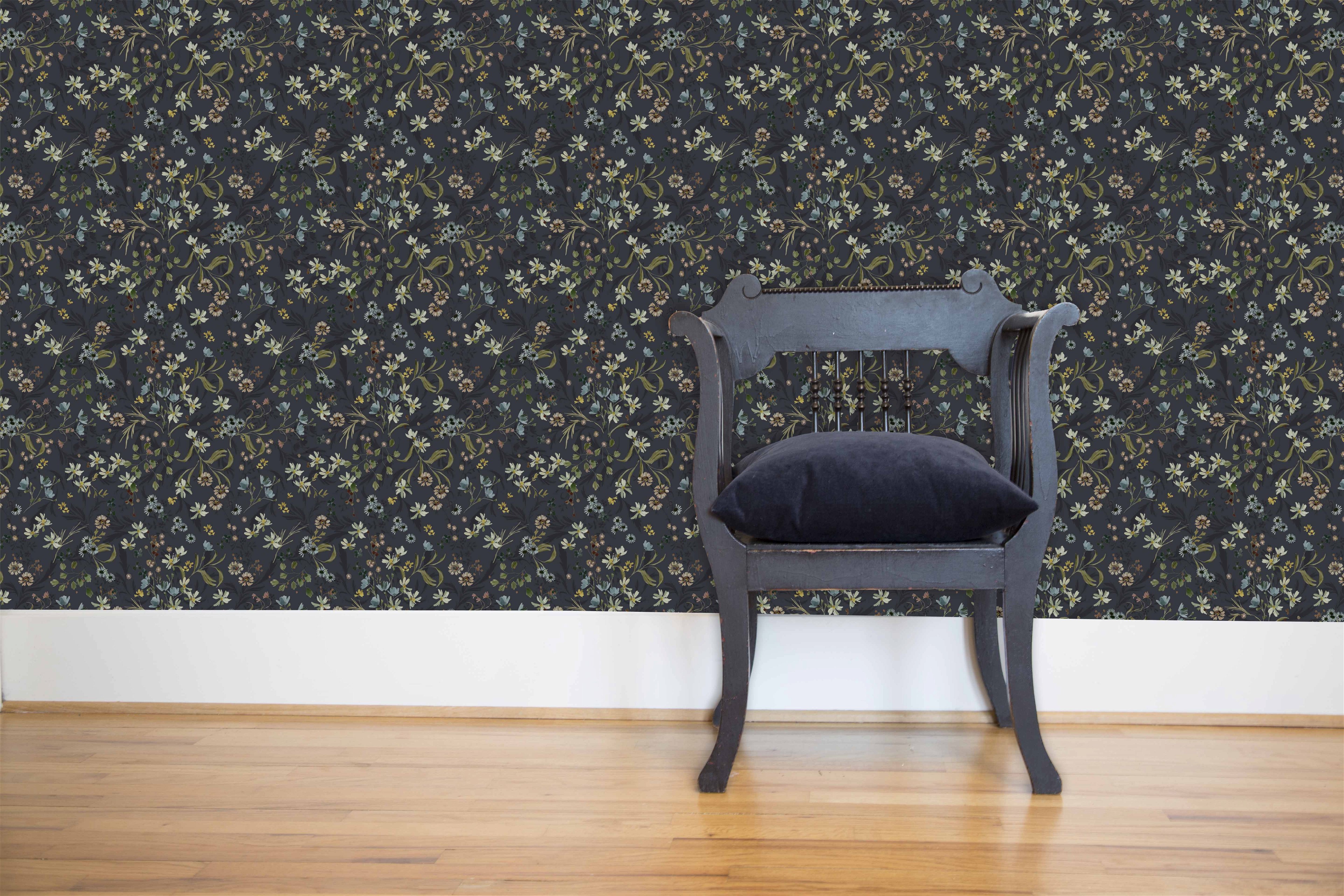 a chair sitting in front of a floral wallpaper