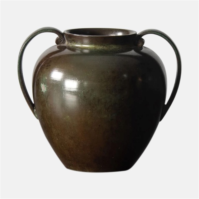 a brown vase with a curved handle on a white background