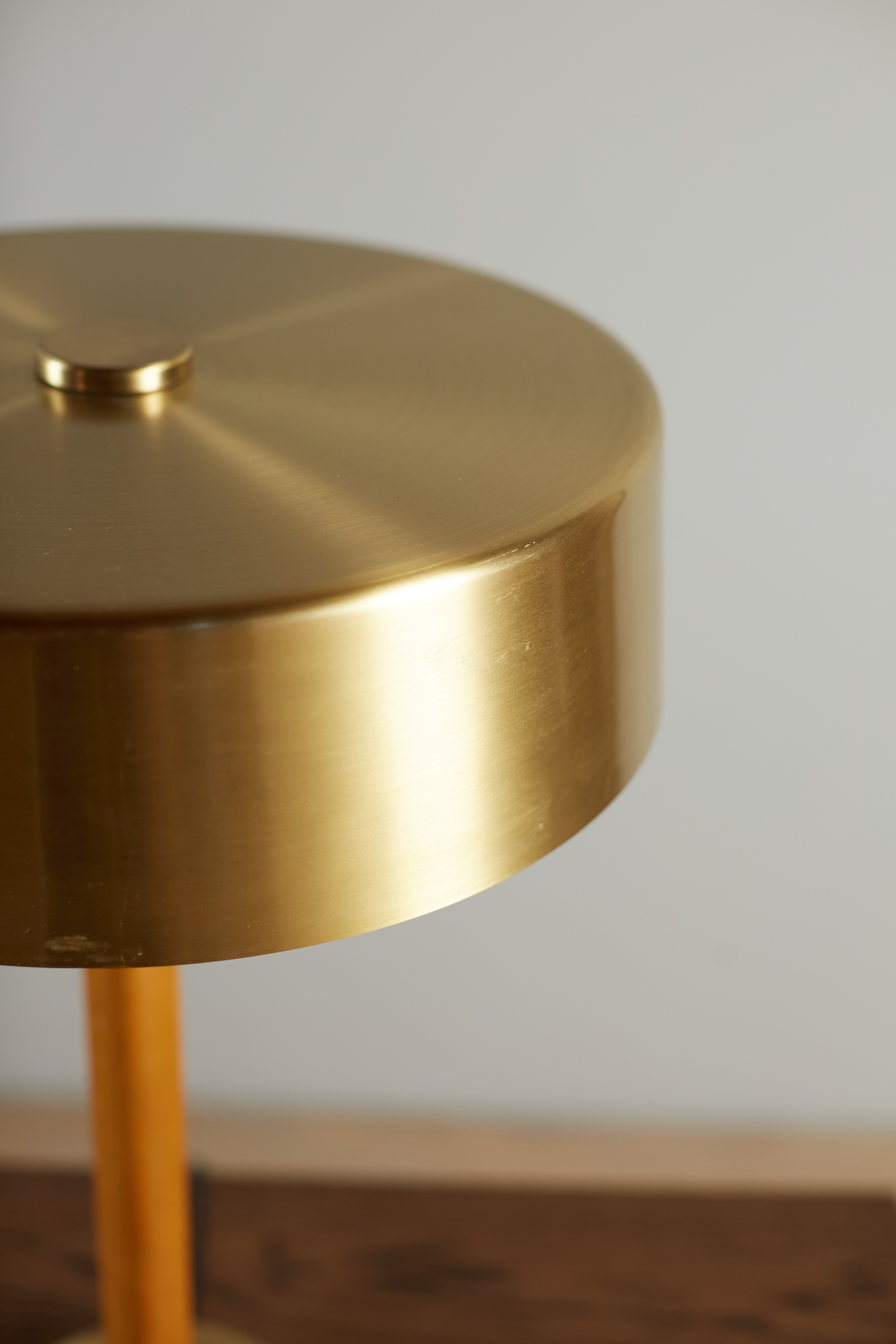 a close up of a gold table lamp on a wooden table