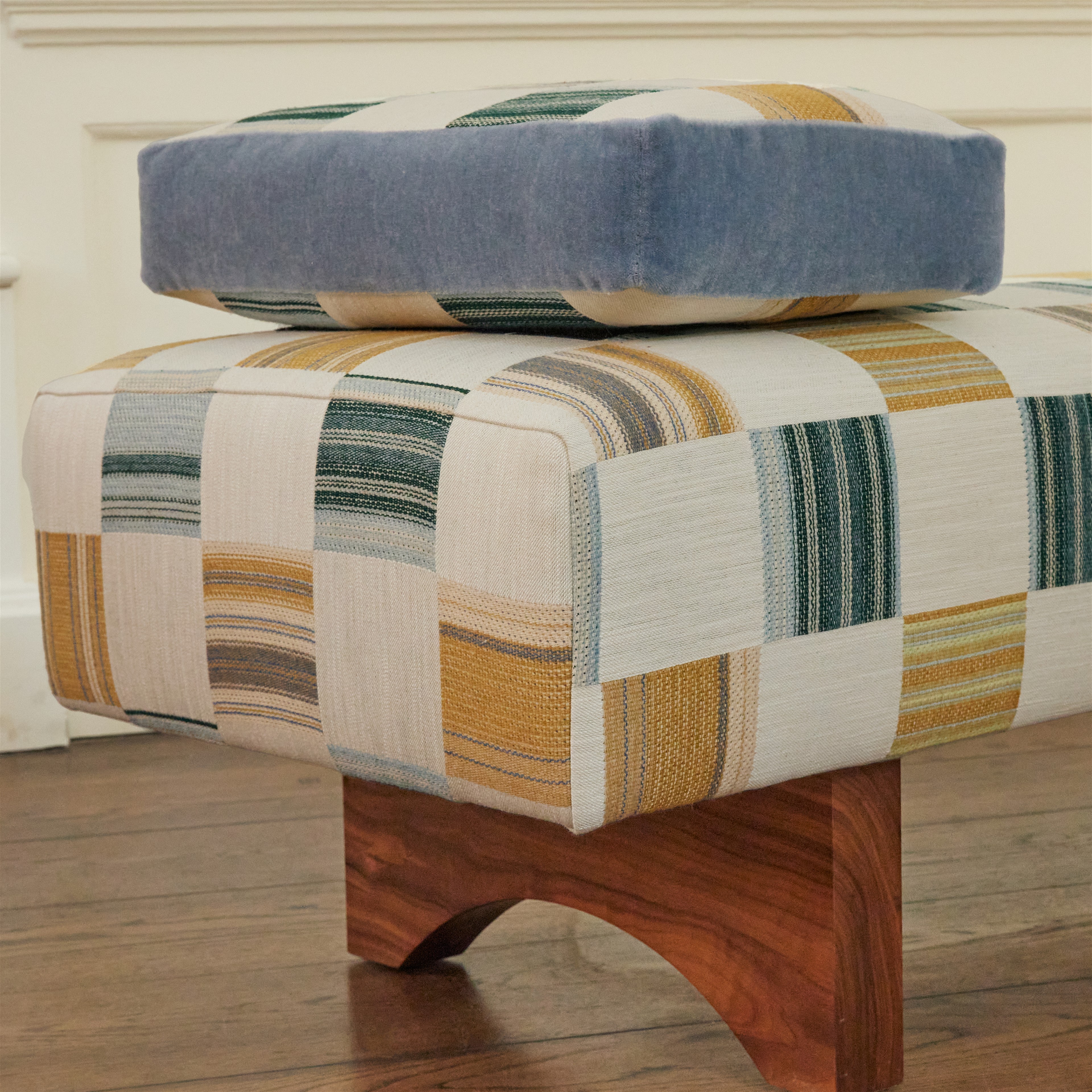 a wooden foot stool with a blue cushion on top of it