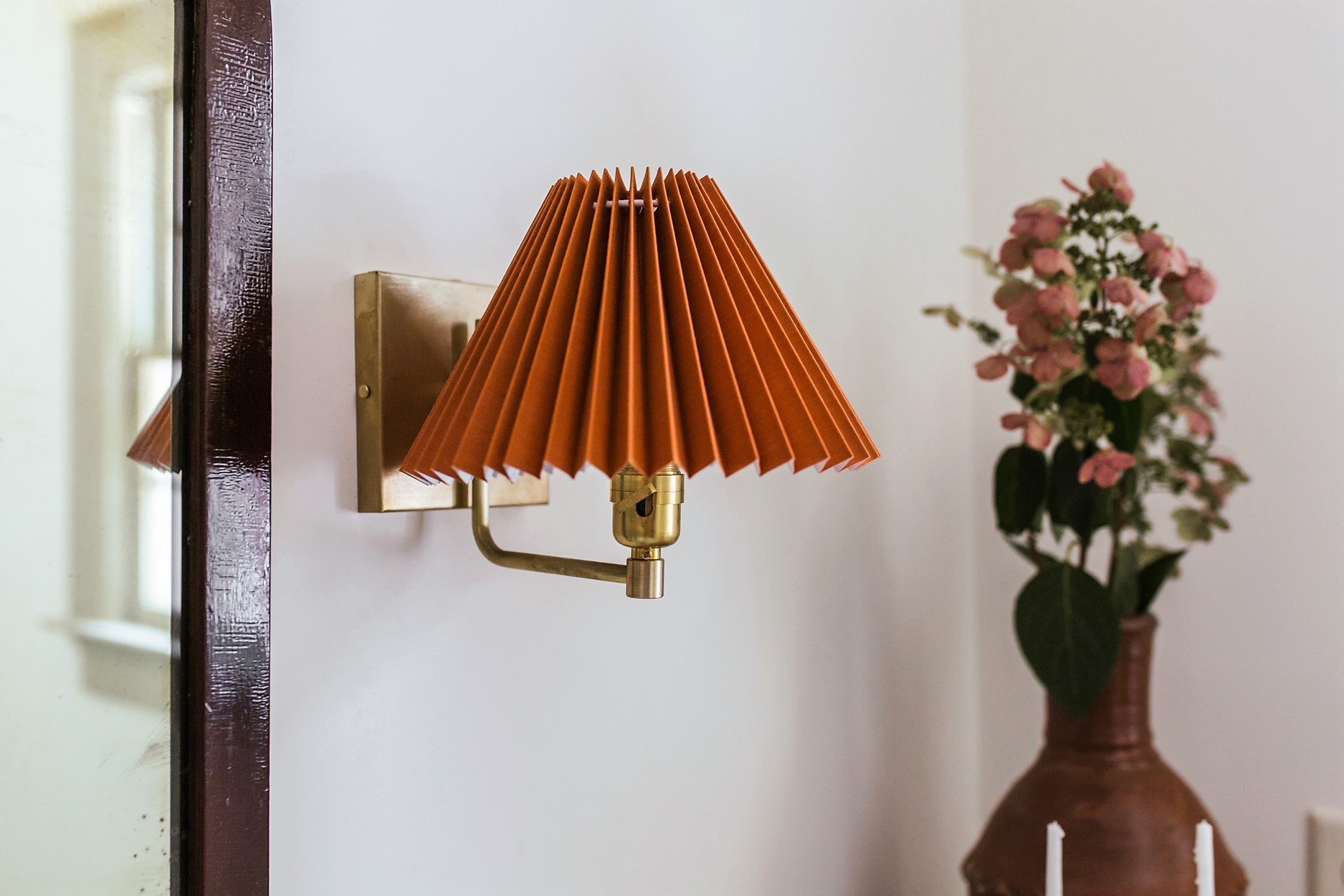 a lamp that is on a wall next to a vase