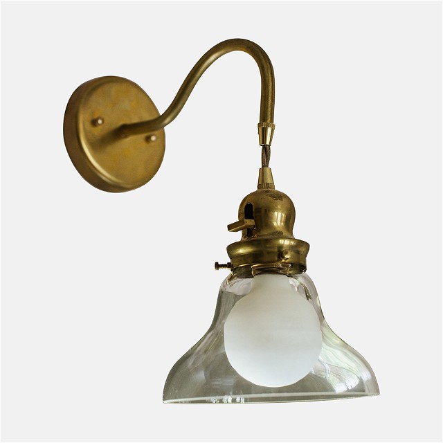 a brass wall light with a glass shade