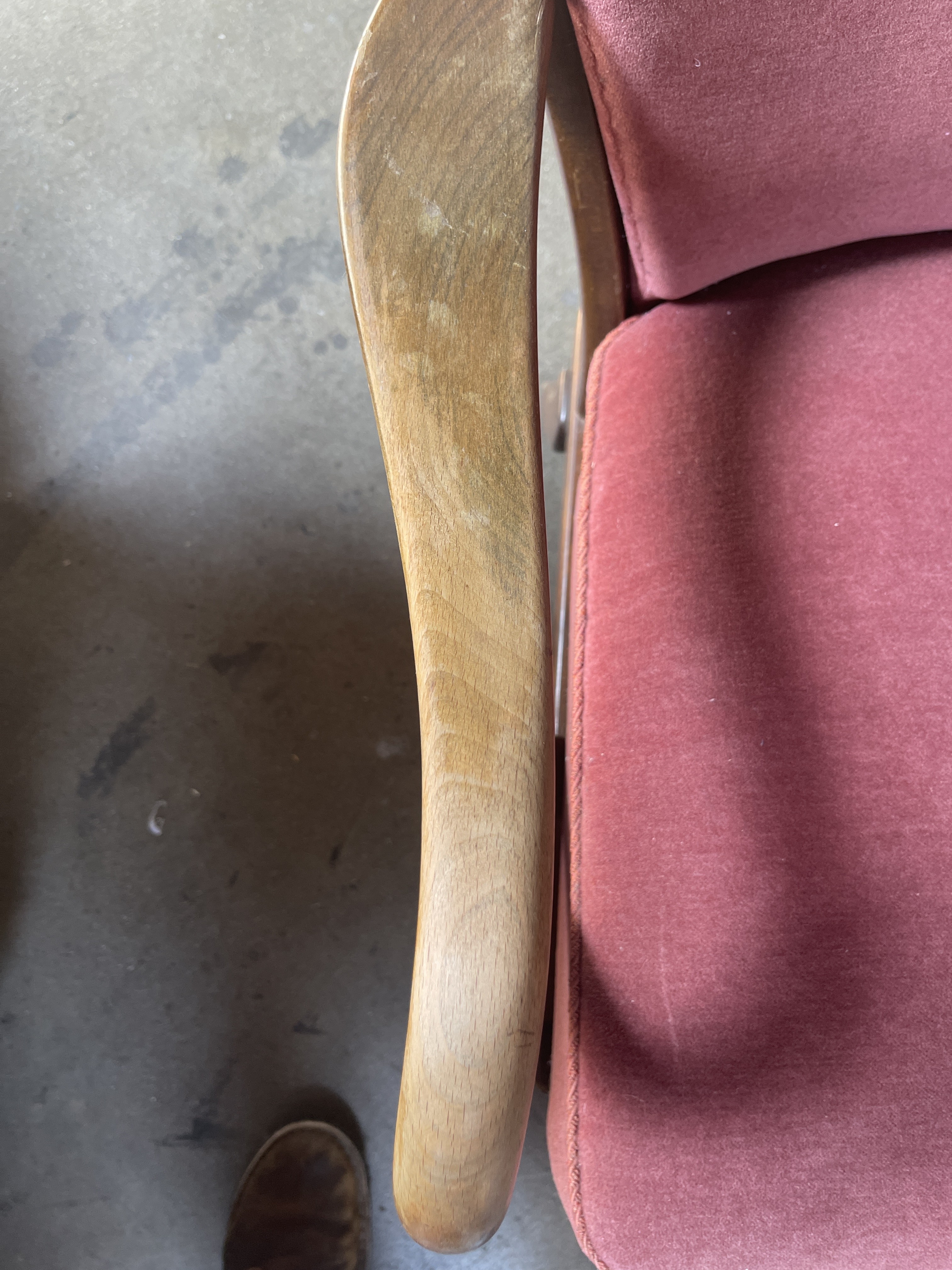a pink chair with a wooden arm rest