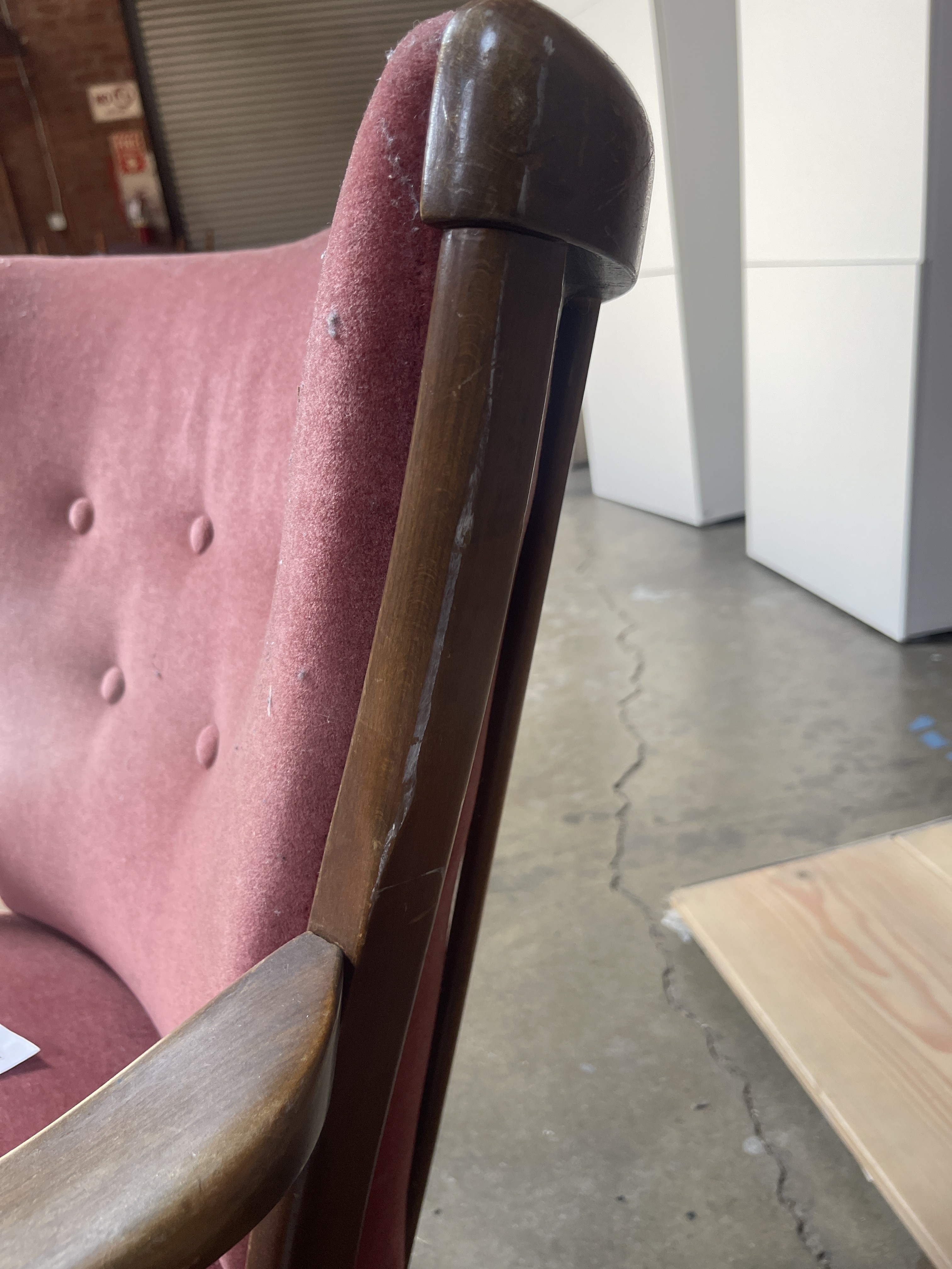 a pink chair with a wooden arm rest