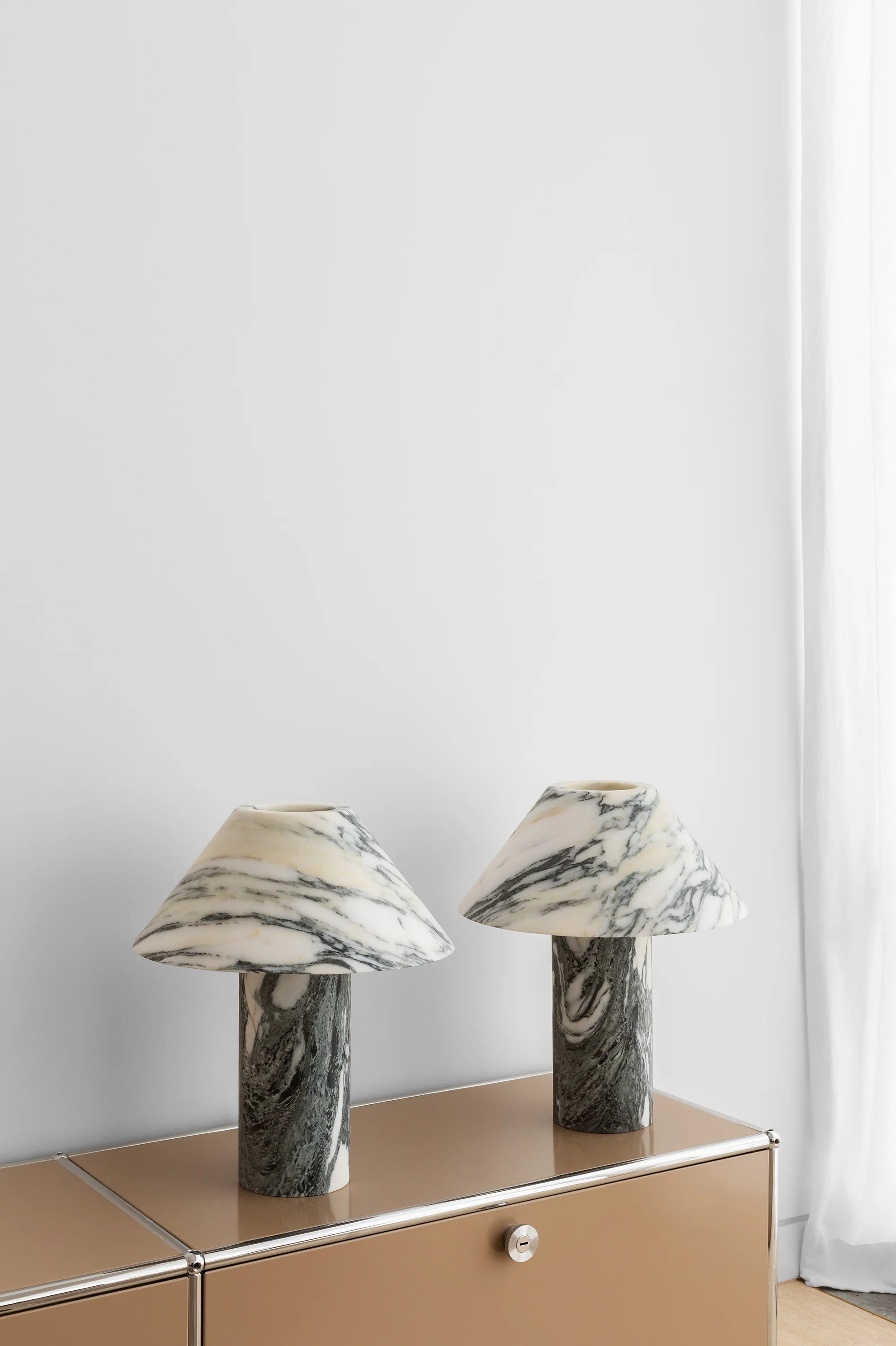 a pair of marble lamps sitting on top of a dresser