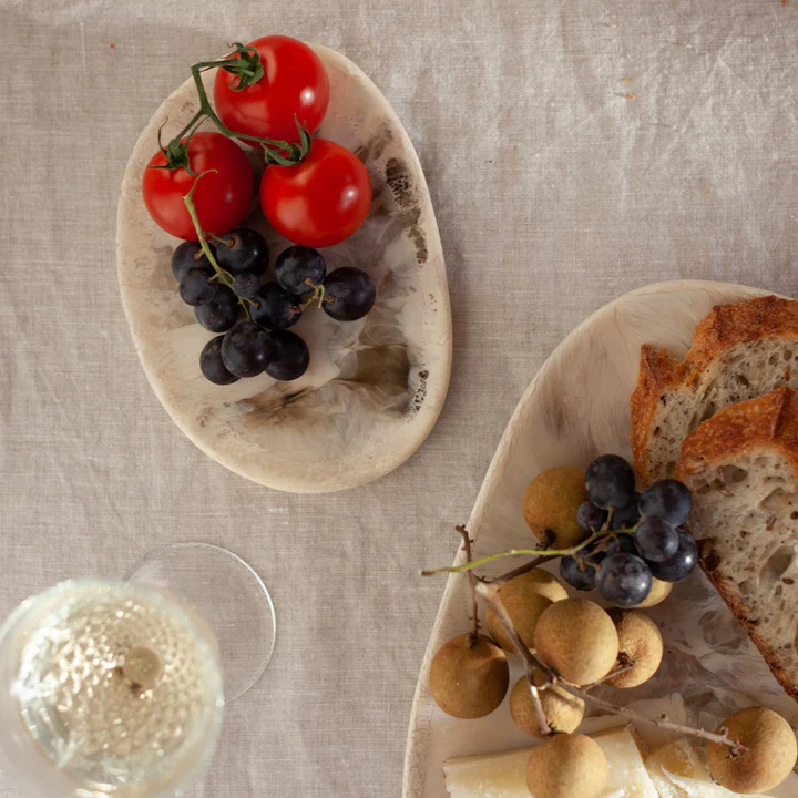 two plates of bread, grapes, and tomatoes on a table