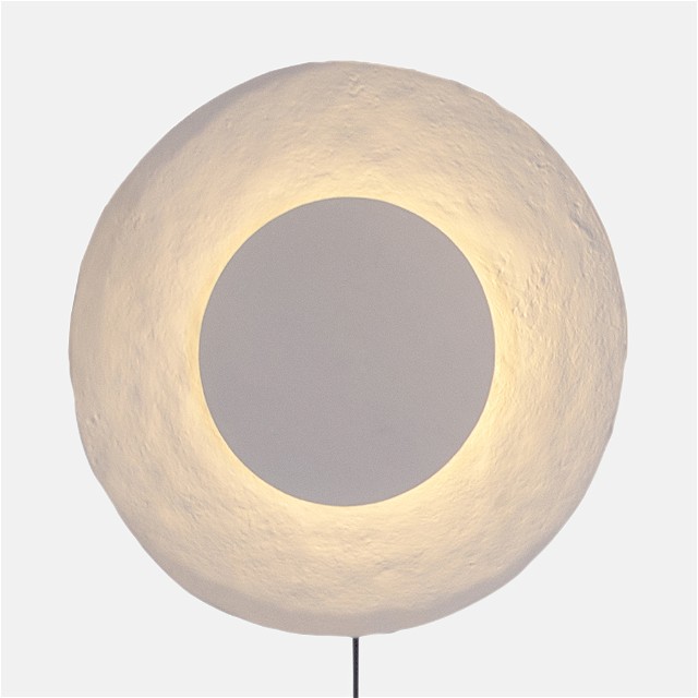 a white circular light sitting on top of a metal pole