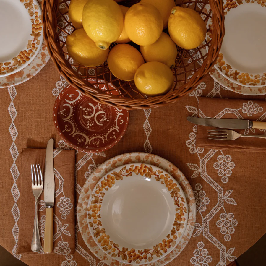 a basket of lemons on a table with a plate and silverware