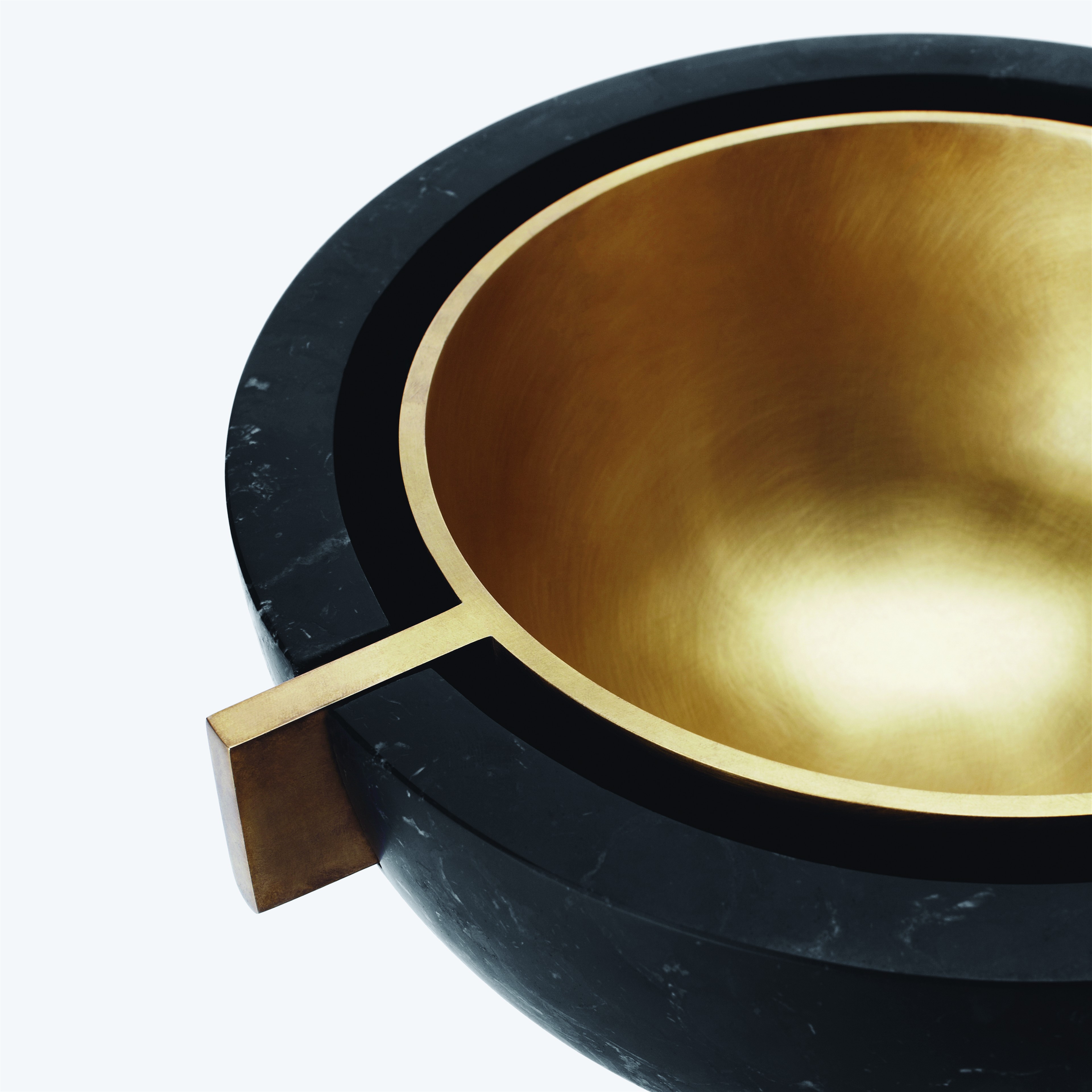 a black and gold bowl with a wooden handle