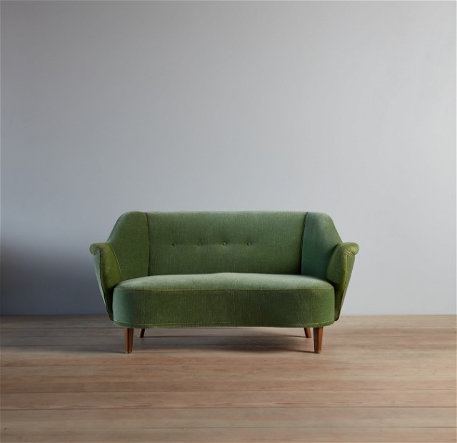 a green couch sitting on top of a wooden floor