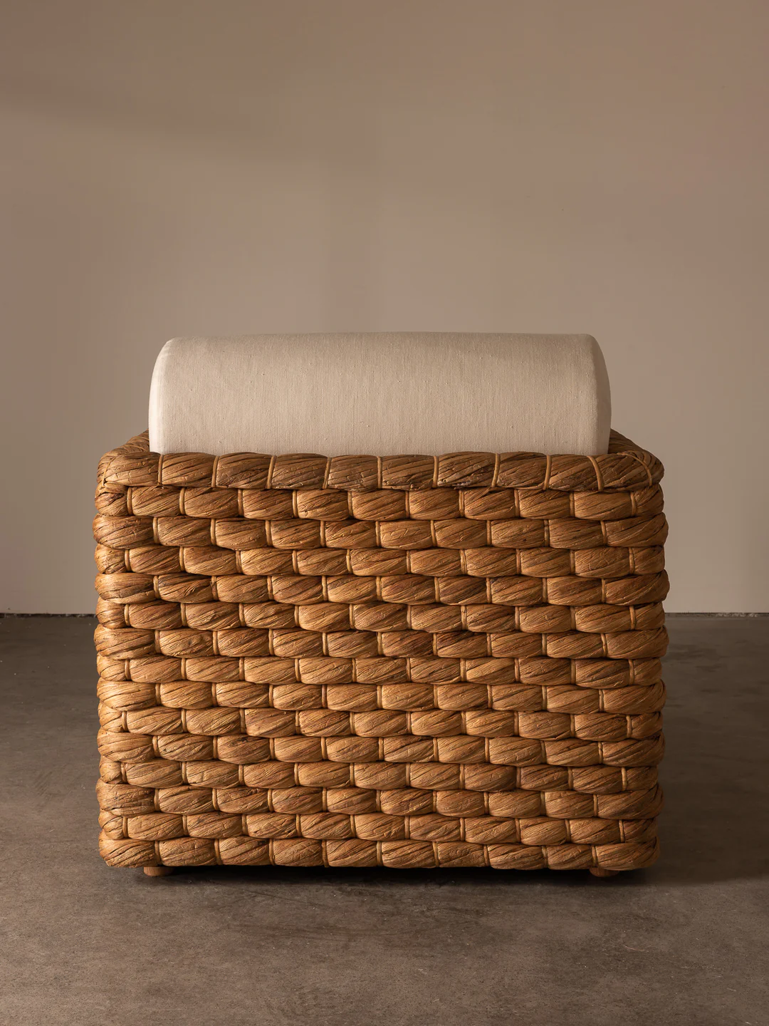 a wicker stool with a white cushion on top of it