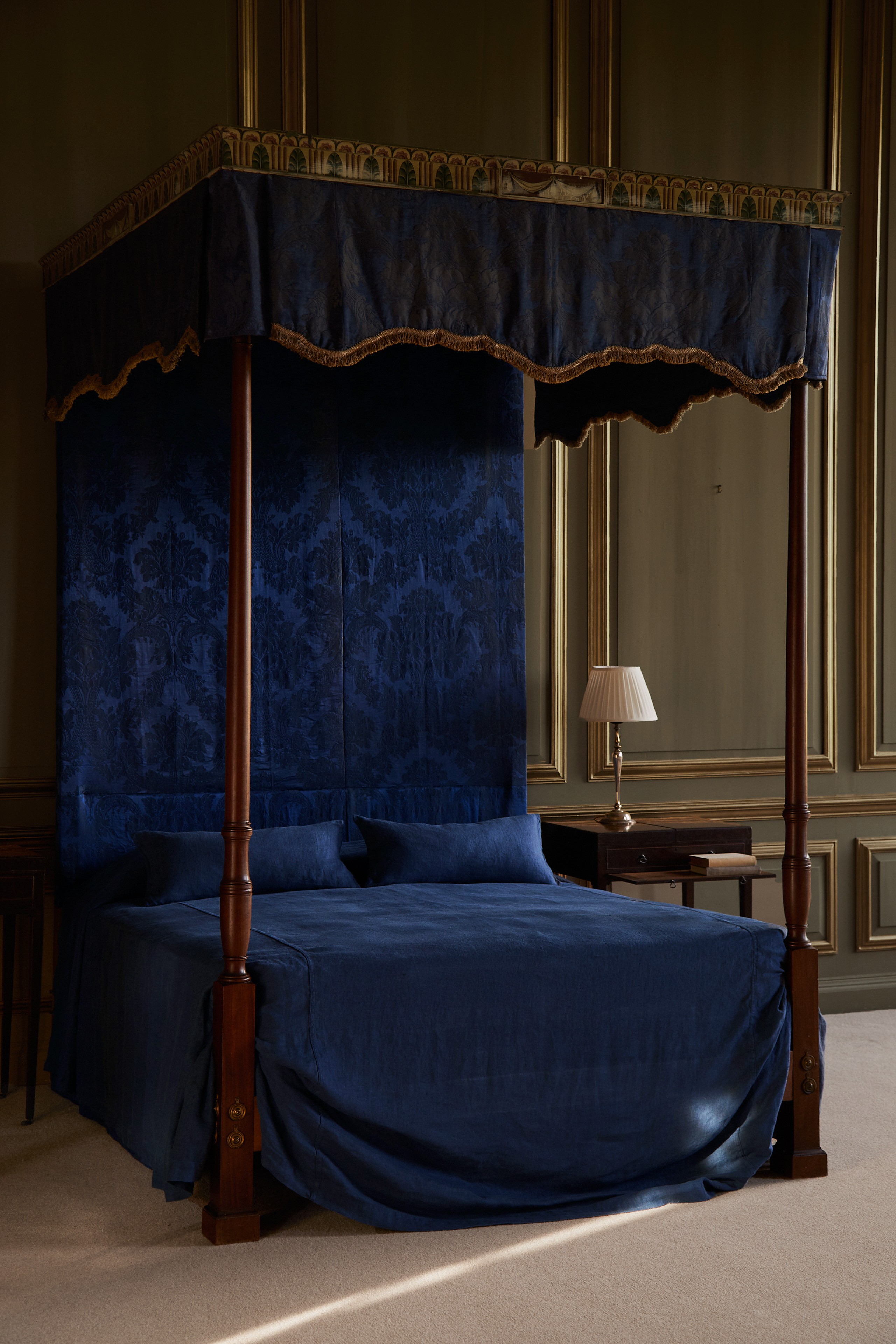 a canopy bed with a blue cover and pillows