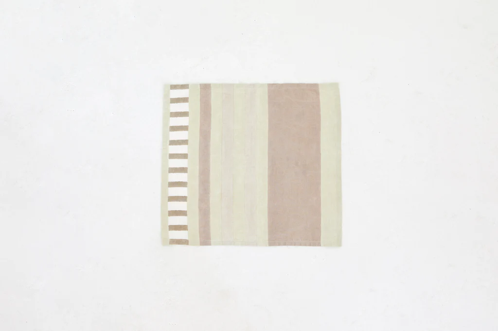 a beige and white striped rug on a white wall