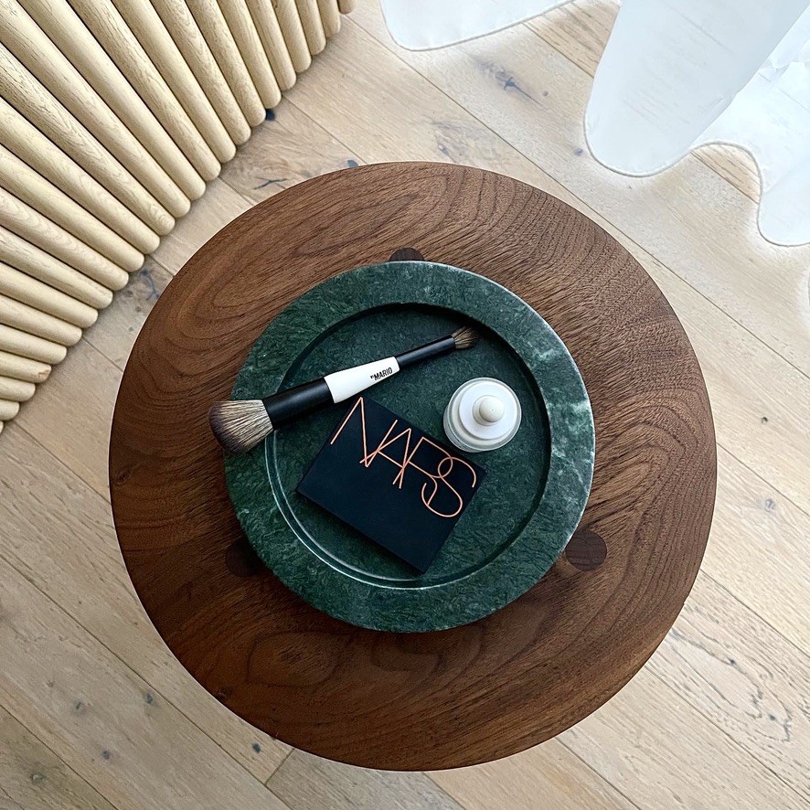 a wooden table topped with a green plate and a brush