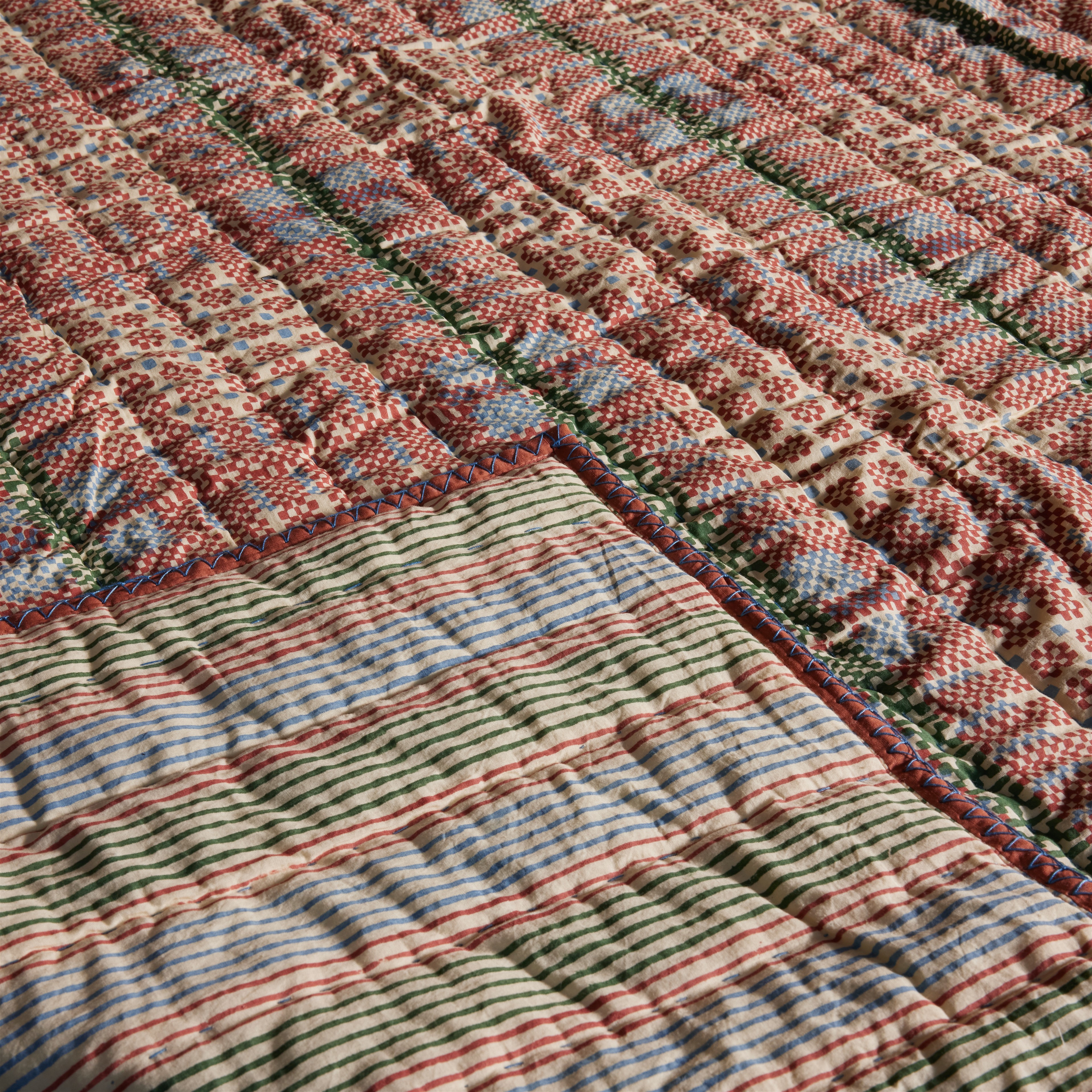 a multicolored quilt is laying on a bed