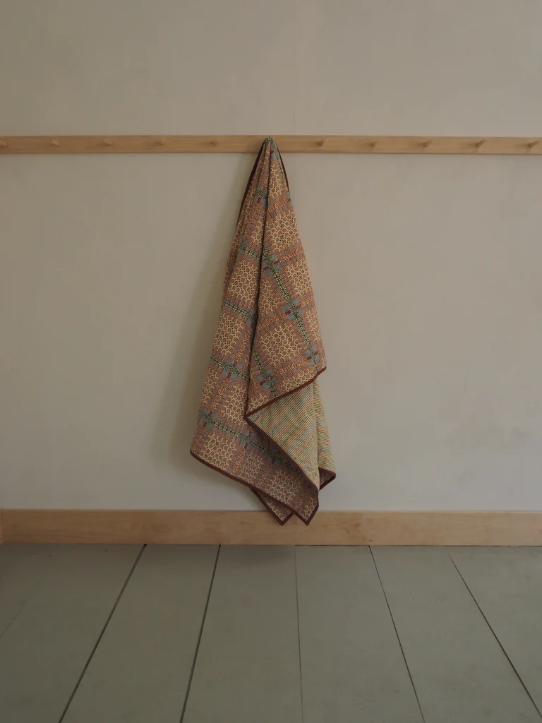 a towel hanging on a wall next to a wooden shelf