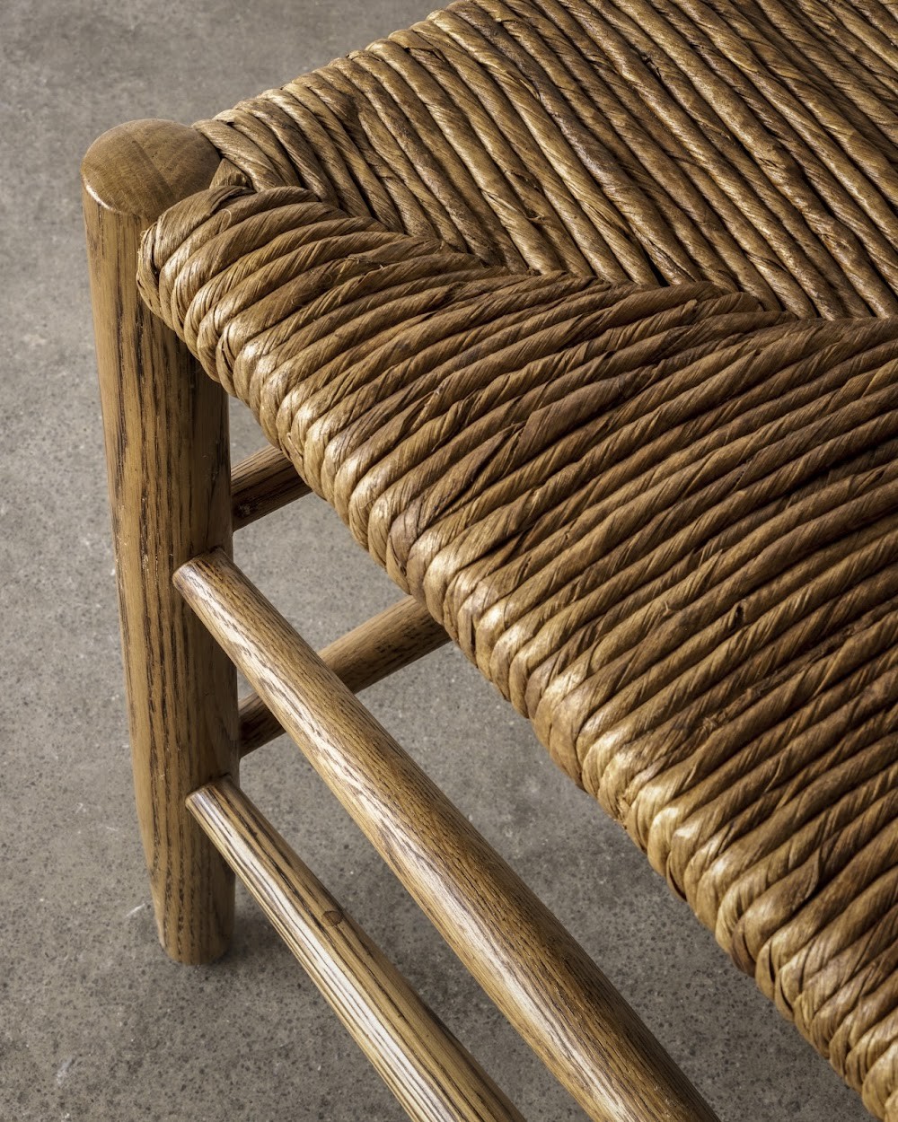 a close up of a wooden bench with a woven seat