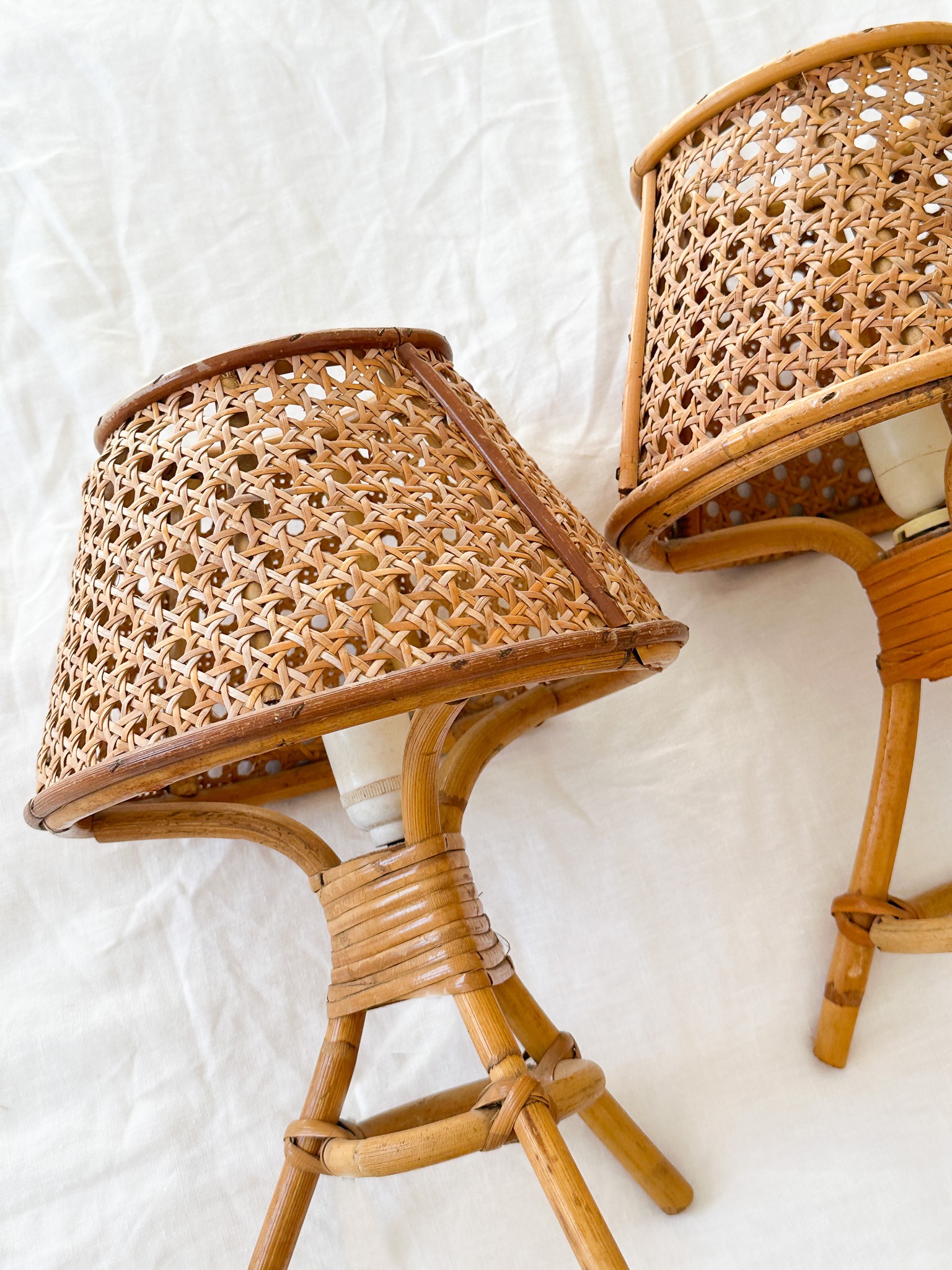 two wicker lamps are sitting on a white sheet