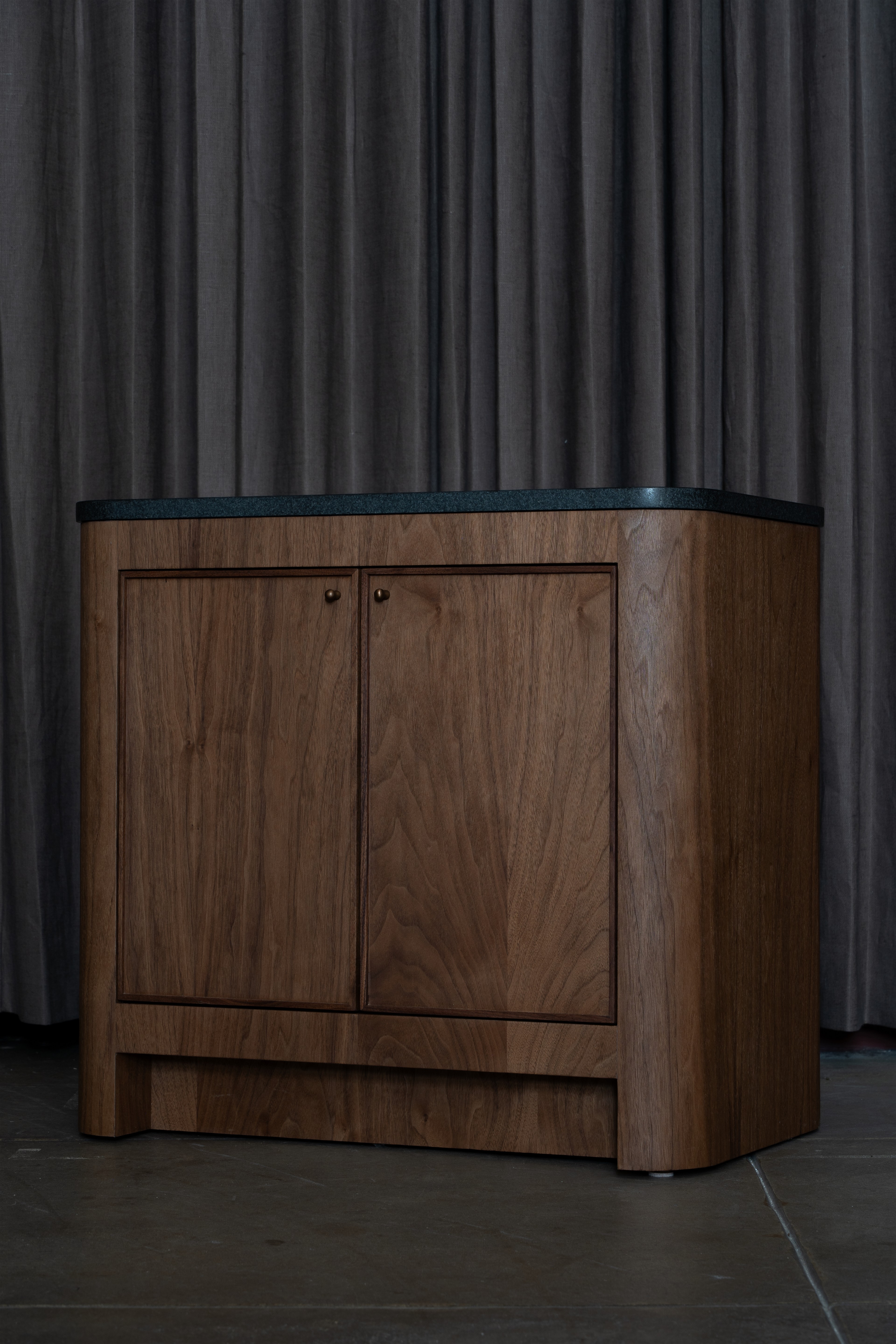 a wooden cabinet with a glass top in front of a curtain