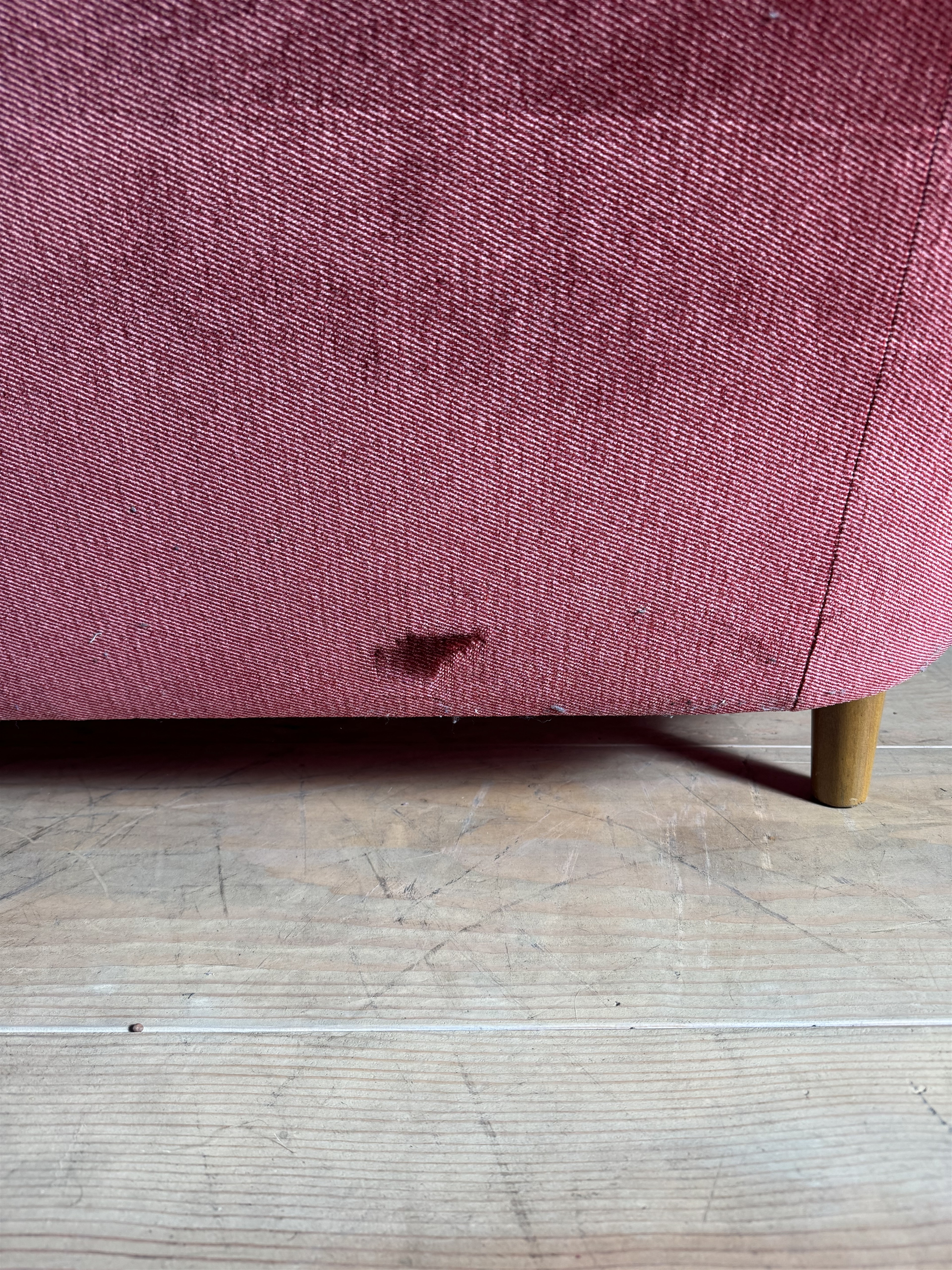 a red couch sitting on top of a wooden floor