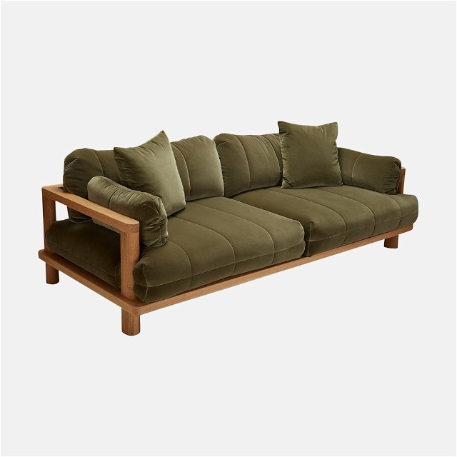 a green couch with a wooden frame and pillows