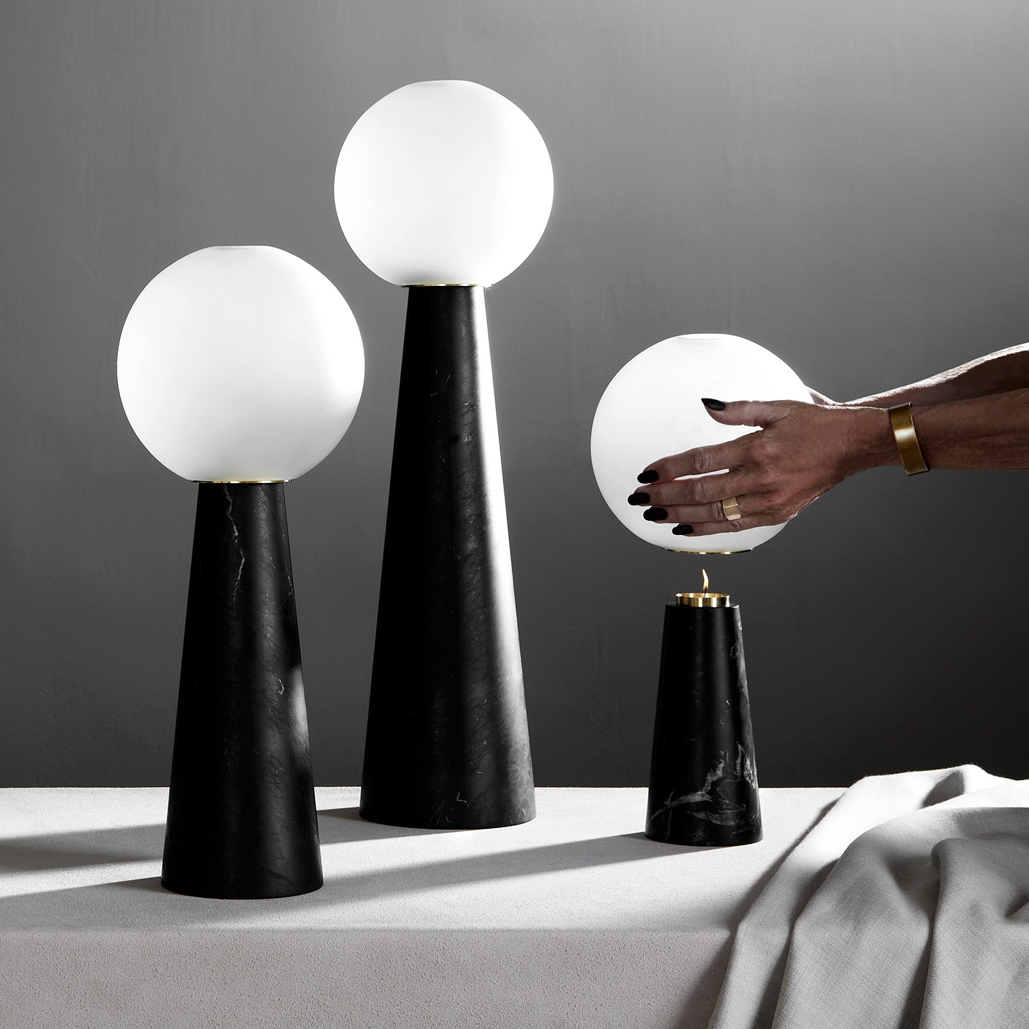 a hand reaching for a ball between two black and white lamps