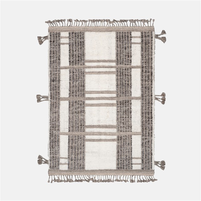 a gray and white rug with tassels