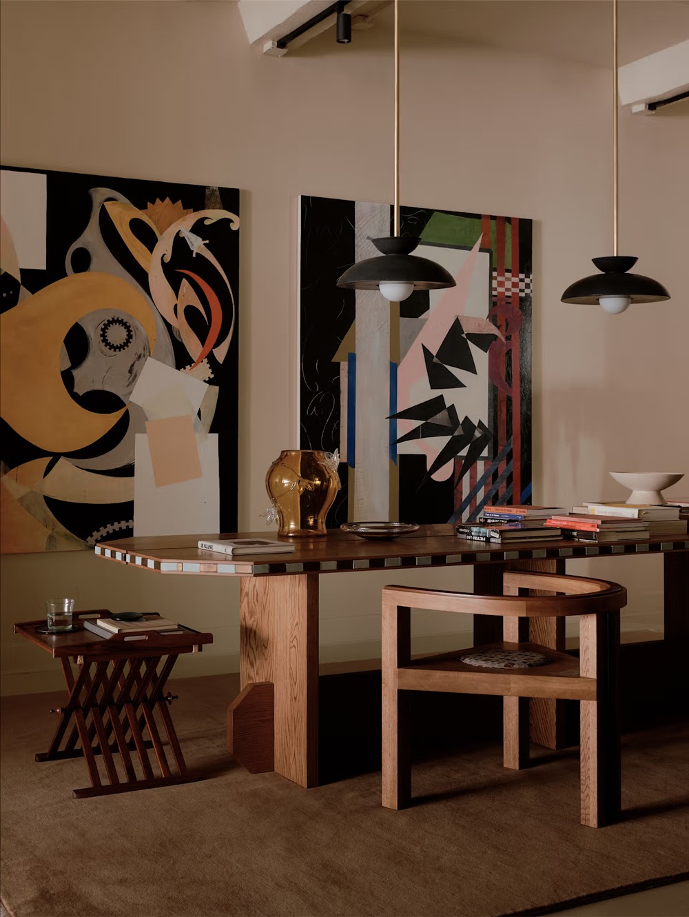 a room with a table, chairs and paintings on the wall