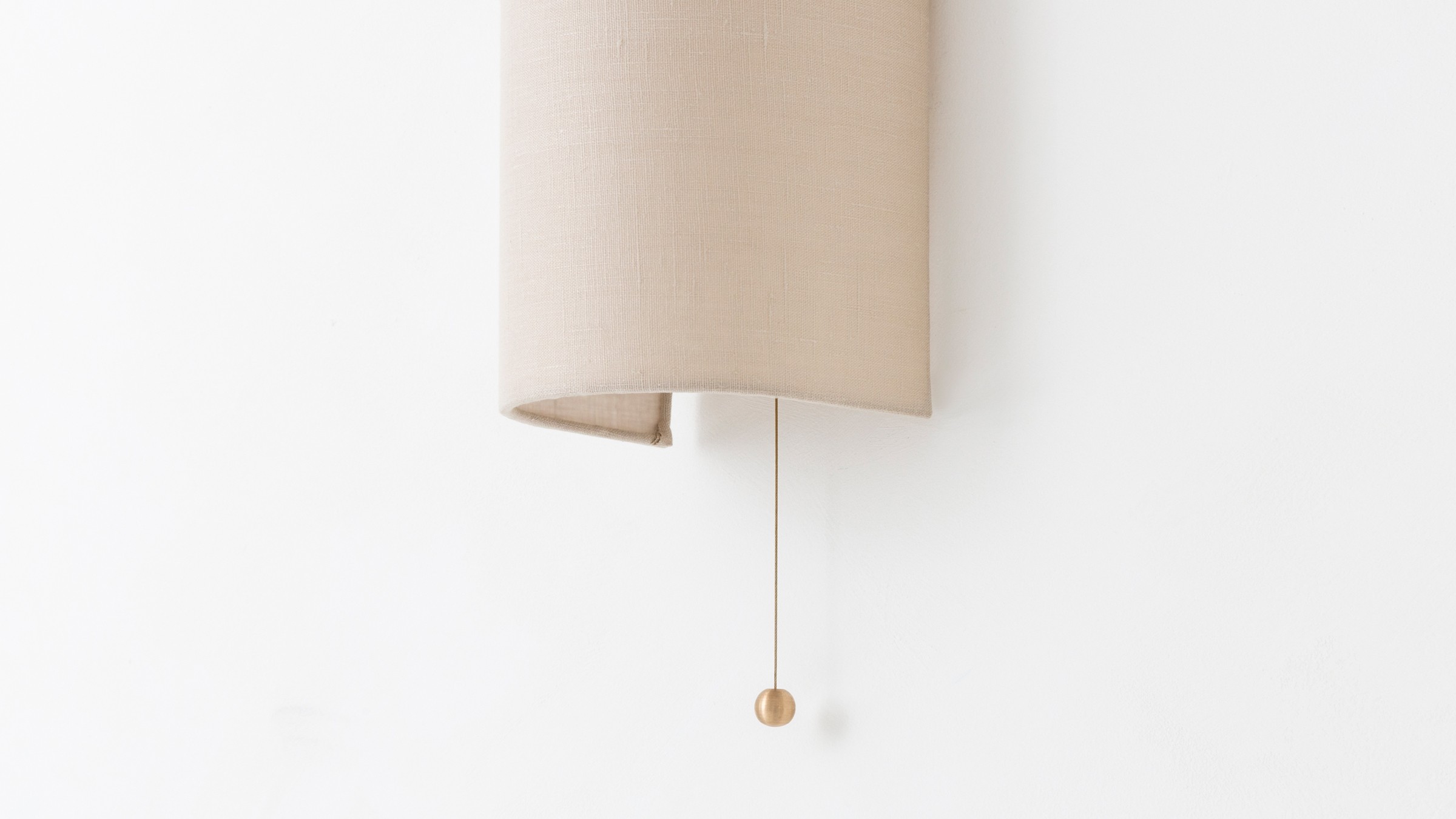 a white wall with a beige lamp hanging from it's side