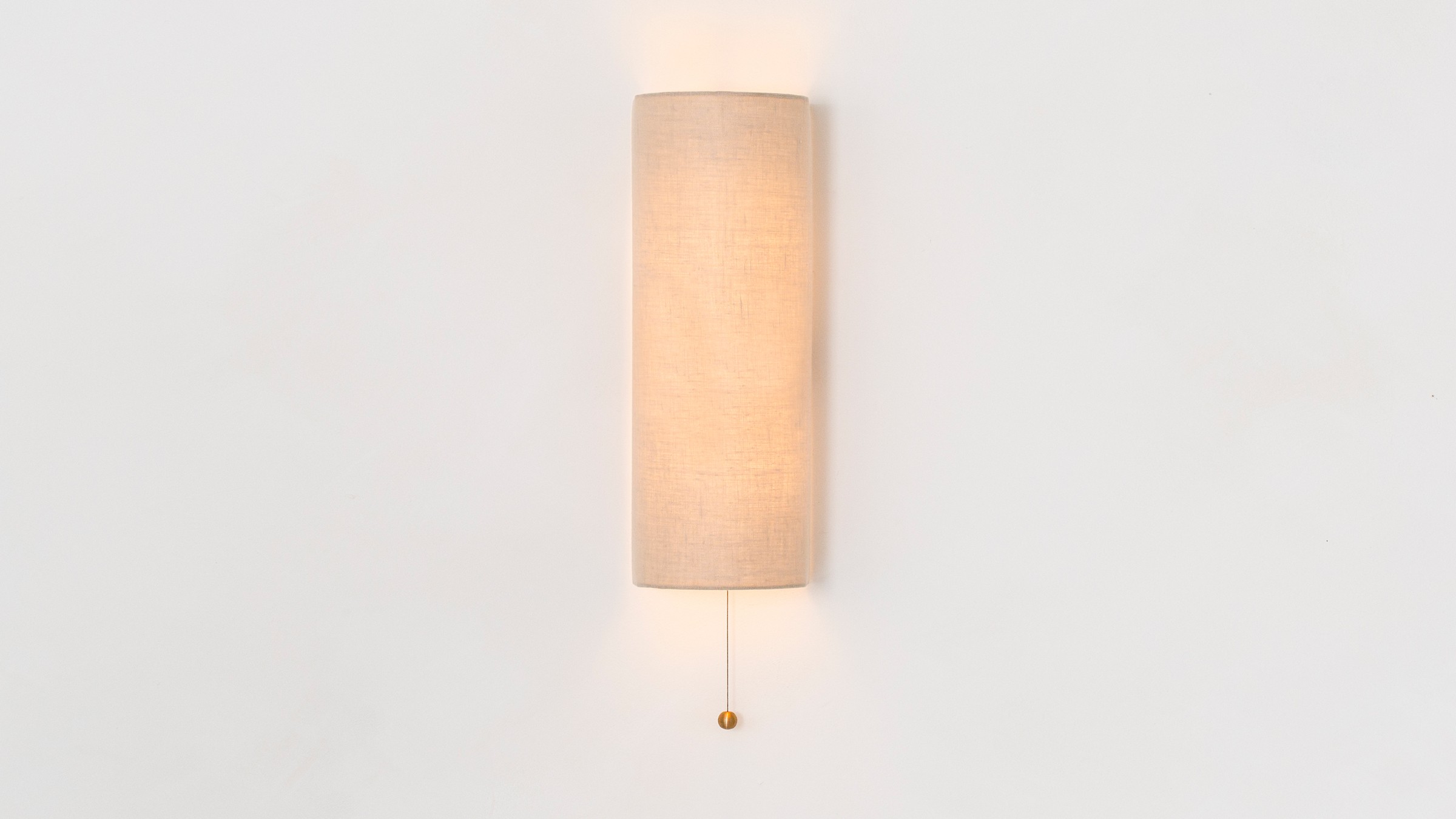 a white wall light with a beige shade